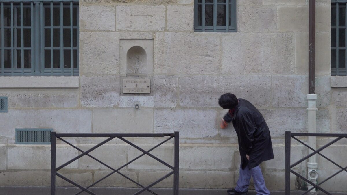 Demonstration for becoming a “professional unemployed” – the artist bending over and wiping while walking along the wall, Rue de Seine, Paris