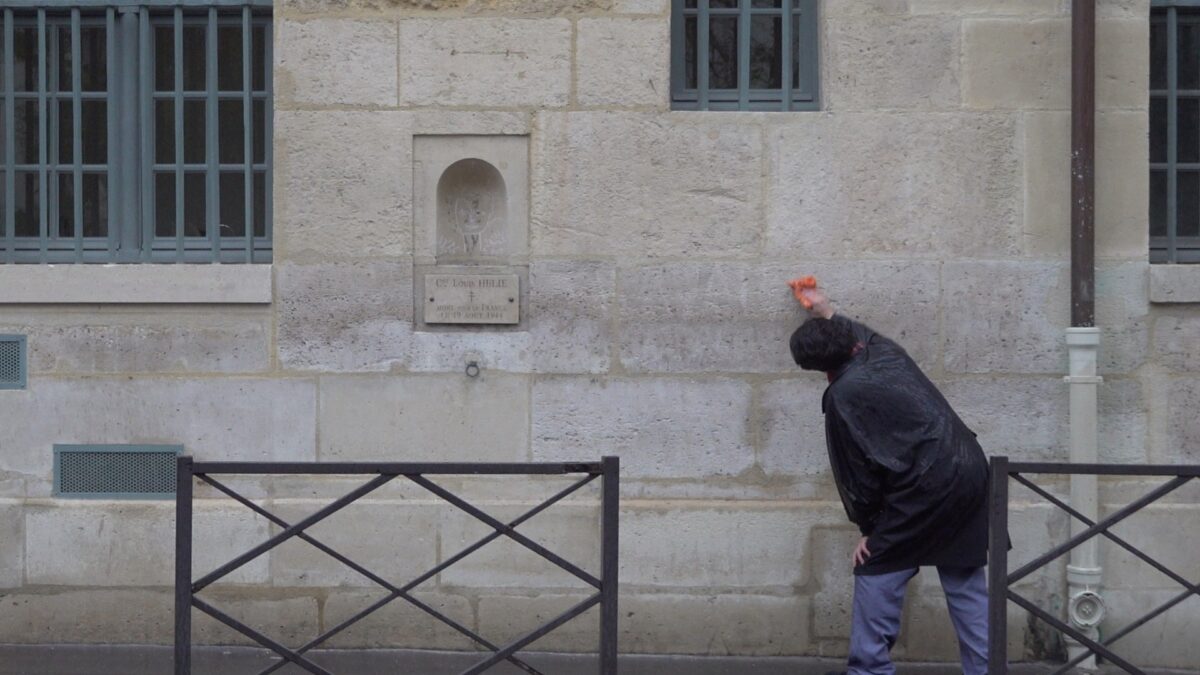 Demonstration for becoming a “professional unemployed” – the artist bending at the waist, one arm outstretched, wiping the wall, Rue de Seine, Paris